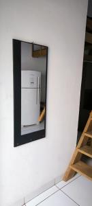 a mirror on a white wall with a refrigerator at Apartamento Loft Confort 02 in Ponta Porã +20 photos
