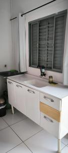 a white kitchen with a sink and a window at Apartamento Loft Confort 02 in Ponta Porã