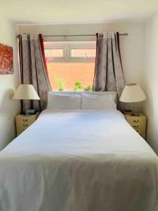 a bedroom with a large white bed with a window at Bramley Fall Park Homestay in Horsforth