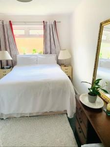 a bedroom with a white bed and a mirror at Bramley Fall Park Homestay in Horsforth