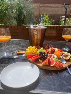 a plate of fruit and vegetables on a table with two glasses at Bramley Fall Park Homestay in Horsforth +10 photos