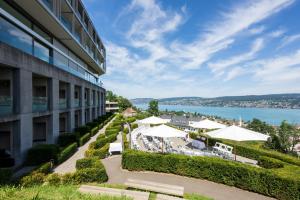 an external view of a building with tables and umbrellas at Hotel Belvoir Lake View & Spa in Rüschlikon