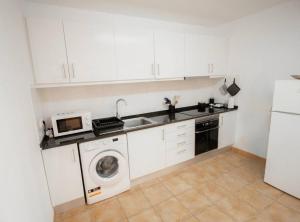 a kitchen with a washing machine and a microwave at Slowing Villas - Villa Âncora in Porto Santo