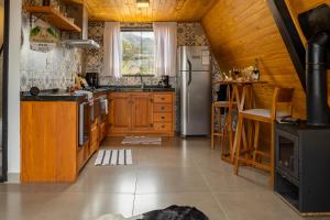 a kitchen with wooden cabinets and a refrigerator at Orvalho da mantiqueira in Gonçalves