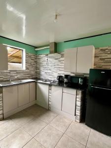 a kitchen with white cabinets and a black refrigerator at La villa d'Isalya in Sainte-Suzanne