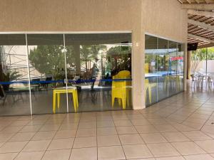 a lobby with yellow tables and chairs in a building at Apartamento Bete Águas da Serra in Caldas Novas