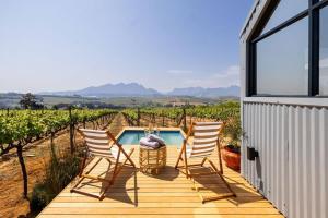 a deck with three chairs and a swimming pool at Stellenbosch Farm Cabin - Klein Frans in Stellenbosch