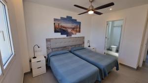 a bedroom with a blue bed and a ceiling fan at Costa Luz Beach Apartments in Puerto del Carmen