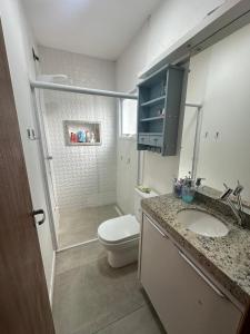 a bathroom with a toilet and a sink and a shower at Casa família local tranquilo in Garopaba +12 photos
