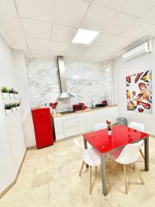 a kitchen with a red table and white chairs at Apartamentos Bobal Requena in Requena