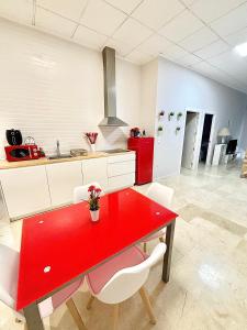 a kitchen with a red table and white cabinets at Apartamentos Bobal Requena in Requena
