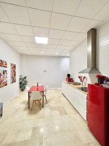 a kitchen with a red table and white cabinets at Apartamentos Bobal Requena in Requena