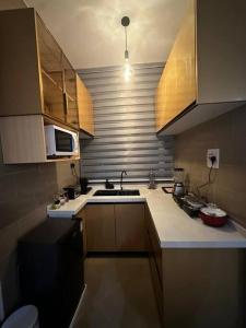 a small kitchen with a sink and a microwave at Cozy 1BR Apt in Kajjansi Airstrip Entebbe in Kajansi