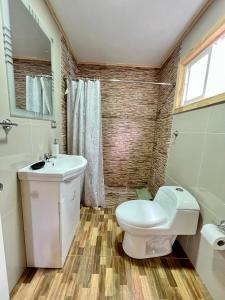 a bathroom with a white toilet and a sink at Cabañas Puntocom in Puerto Aisén +35 photos