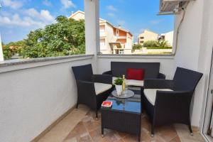 balkon z krzesłami i stołem z czerwoną poduszką w obiekcie Apartment Kety w Novalji