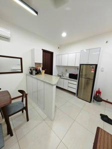 Una cocina con gabinetes blancos y un refrigerador. en K Avenue Homestay, en Kota Kinabalu 3 fotos más
