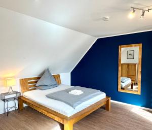 a bedroom with a bed with blue walls and a mirror at MEINpartments - Full service living Apartmenthouse in Wolfsburg
