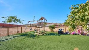 a playground with a swing set in the grass at Luxurious Villa in Prado del Rey with Pool in Prado del Rey