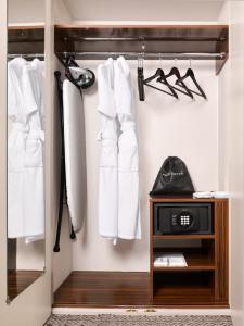 a closet with white clothes and a clock in it at Strand Palace in London