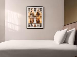 a bedroom with a white bed with a picture on the wall at Strand Palace in London