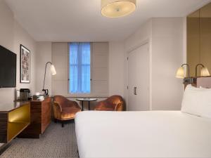 a hotel room with a bed and a desk and chairs at Strand Palace in London
