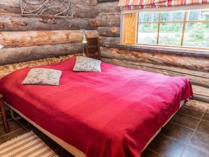 ein Schlafzimmer mit einem roten Bett in einer Blockhütte in der Unterkunft Holiday Home Villa olivia by Interhome in Rukatunturi 