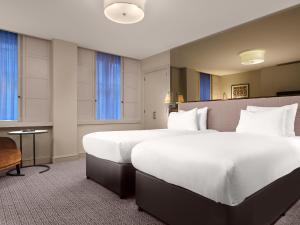 a large white bed in a hotel room at Strand Palace in London
