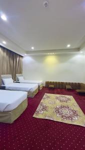 a hotel room with two beds and a red carpet at فندق جواهر الهدى in Makkah +40 photos