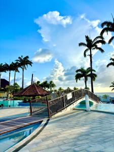 a bridge over a swimming pool with palm trees at Studio Zandoli P&V in Sainte-Luce