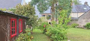 un jardín con puertas rojas y árboles y una casa en Porte 5, en Valognes