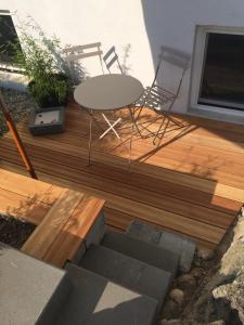 a wooden deck with a table and chairs on it at Chiemgau-ROOM, helles Souterrain, eigene Terrasse in Riedering