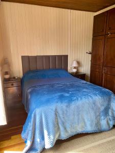 a bedroom with a bed with a blue blanket at Suite 391 - Quarto privativo em casa in Canela
