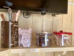 a shelf with containers of utensils and a microwave at Suite 391 - Quarto privativo em casa in Canela