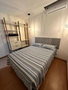 a bedroom with a bed with a striped blanket at 1204 Apto 2 Quartos Cabedelo Ponta de Campina Cabedelo TAXA DE ENERGIA E LIMPEZA SÃO COBRADAS NO CHECK-IN E CHECK-OUT in Cabedelo