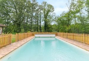 a swimming pool in a backyard with a wooden fence at Gîtes les Muids - Les "Oiseaux" et la "Ferme" in Brinon-sur-Sauldre