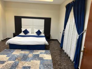 a bedroom with a king sized bed with blue curtains at خزامى ابها للشقق المخدومة in Abha