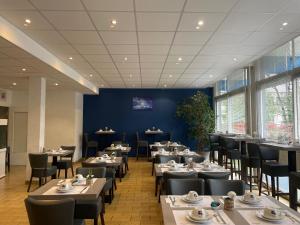 a restaurant with tables and chairs and a blue wall at The Originals City, Hôtel Villancourt, Grenoble Sud in Le Pont-de-Claix