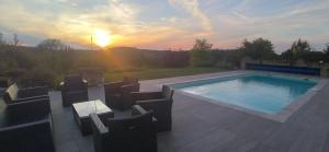 a swimming pool with chairs and the sunset in the background at Les Terrasses du Carlat, Le Logis, Demeure raffinée, situation idéale Dordogne, vues, piscine in Saint-Cybranet
