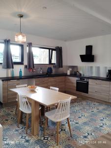 a kitchen with a wooden table and white chairs at Gite de la salamandre in Pléguien