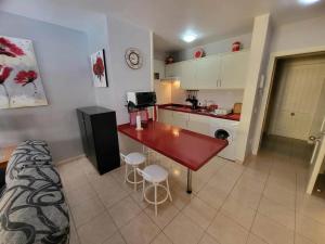 a kitchen with a red table in a room at Olivia Sunset 31 - One Bed in Puerto de Santiago