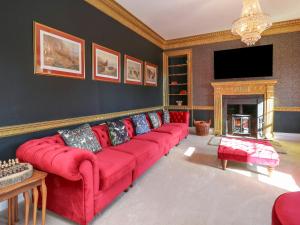 a living room with a red couch and a fireplace at Llwynderw Hall in Llanwrtyd Wells
