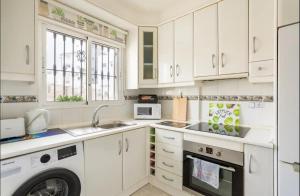 a kitchen with white cabinets and a washer and dryer at Orihuela Costa Sleeps 6 with Roof Terrace & Pool in Villacosta