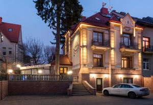 um carro branco estacionado em frente a um edifício em Villa Stanislavskyi Hotel em Lviv