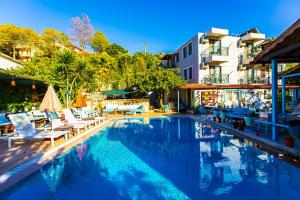 ein großes Schwimmbecken mit Liegestühlen und Tischen in der Unterkunft TUTHALİYA HOTEL in Gelemiş