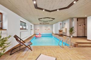 a large indoor pool with a pink pool noodle in a building at Luxus-Villa mit Indoorpool, Sauna & offenem Kamin in Siegsdorf
