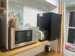 a microwave and a television on a shelf at Addison B&B in Guildford