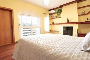 ein Schlafzimmer mit einem großen weißen Bett und einem Kamin in der Unterkunft Rosa Casa Dália in Gramado
