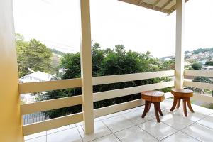 einen Balkon mit 2 Stühlen und Aussicht in der Unterkunft Rosa Casa Dália in Gramado