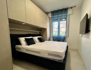 a bedroom with a large bed with white sheets and a window at Appartamento Conchiglia-Immobili e Soluzioni Rent in Lido Adriano