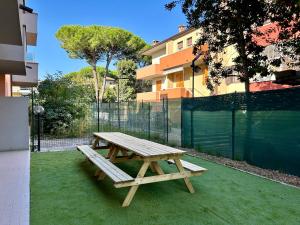 a wooden picnic table sitting on top of green grass at Appartamento Conchiglia-Immobili e Soluzioni Rent in Lido Adriano